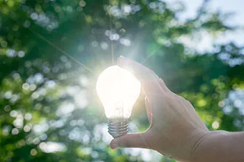 Hand hält LED-Lampe gegen die Sonne